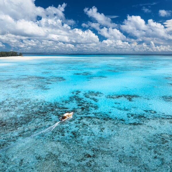 Mare cristallino con barriera corallina e barca nell'Oceano Indiano a Zanzibar